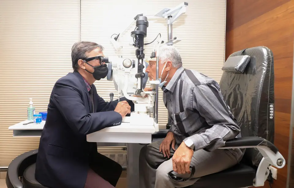 A doctor examining an older patient at the slit lamp