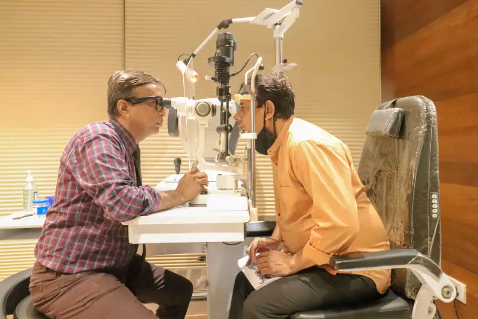 A doctor examining a patient's eyes at the slit lamp